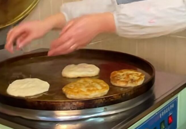 重庆美女路边卖葱油饼,5元一个,现做现吃,客人排队来买